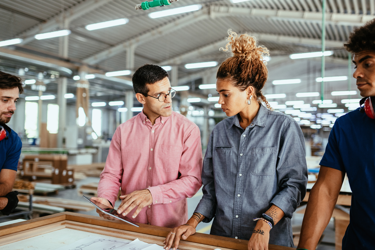 Architects, engineers and blue collar staff working together in modern factory