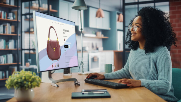 Smiling Woman Using Desktop Computer with Clothing Online Web Store to Choose and Buy Clothes from New Collection.